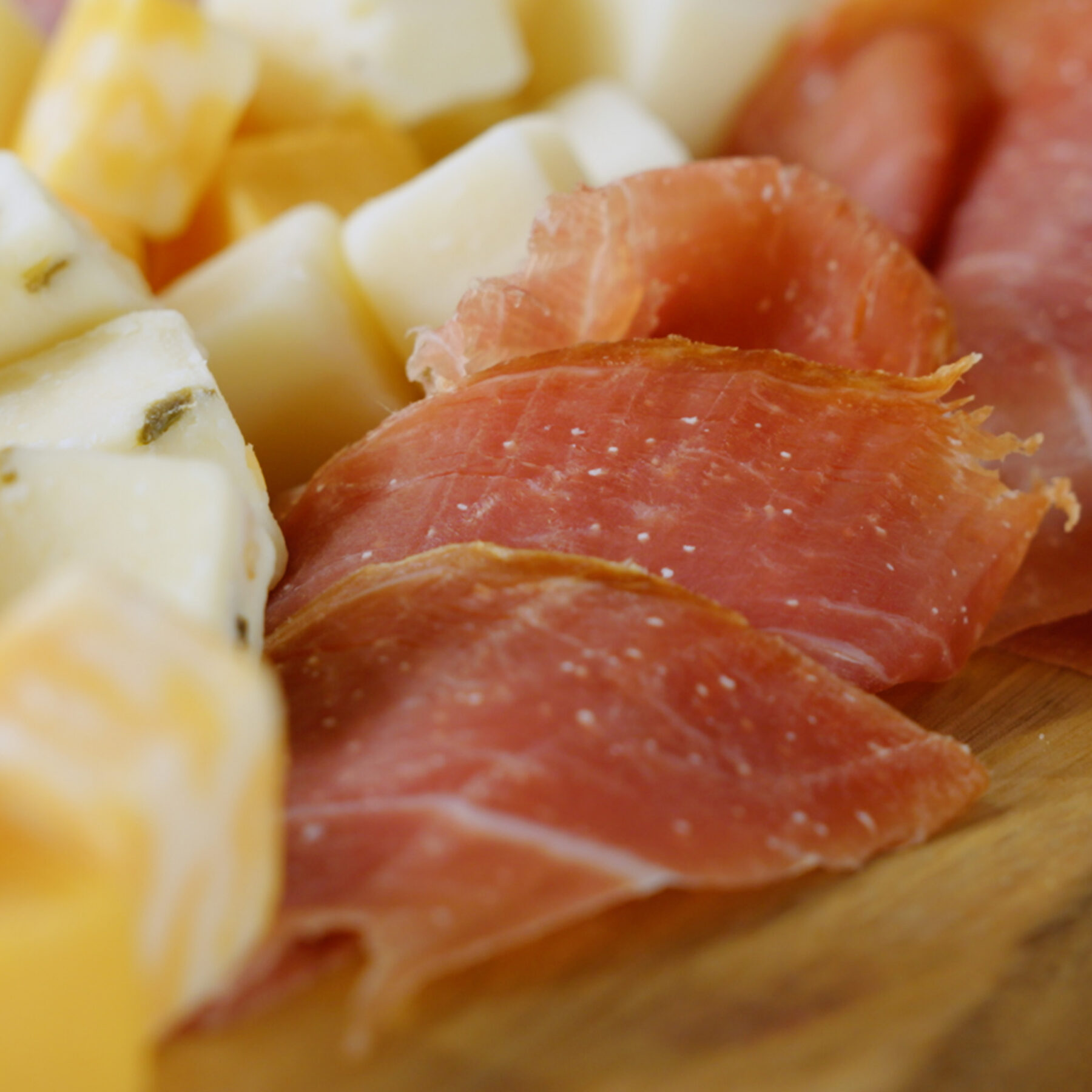 Upper Cut Half Serrano Ham Leg on a plate with Upper Cut cubed cheeses.